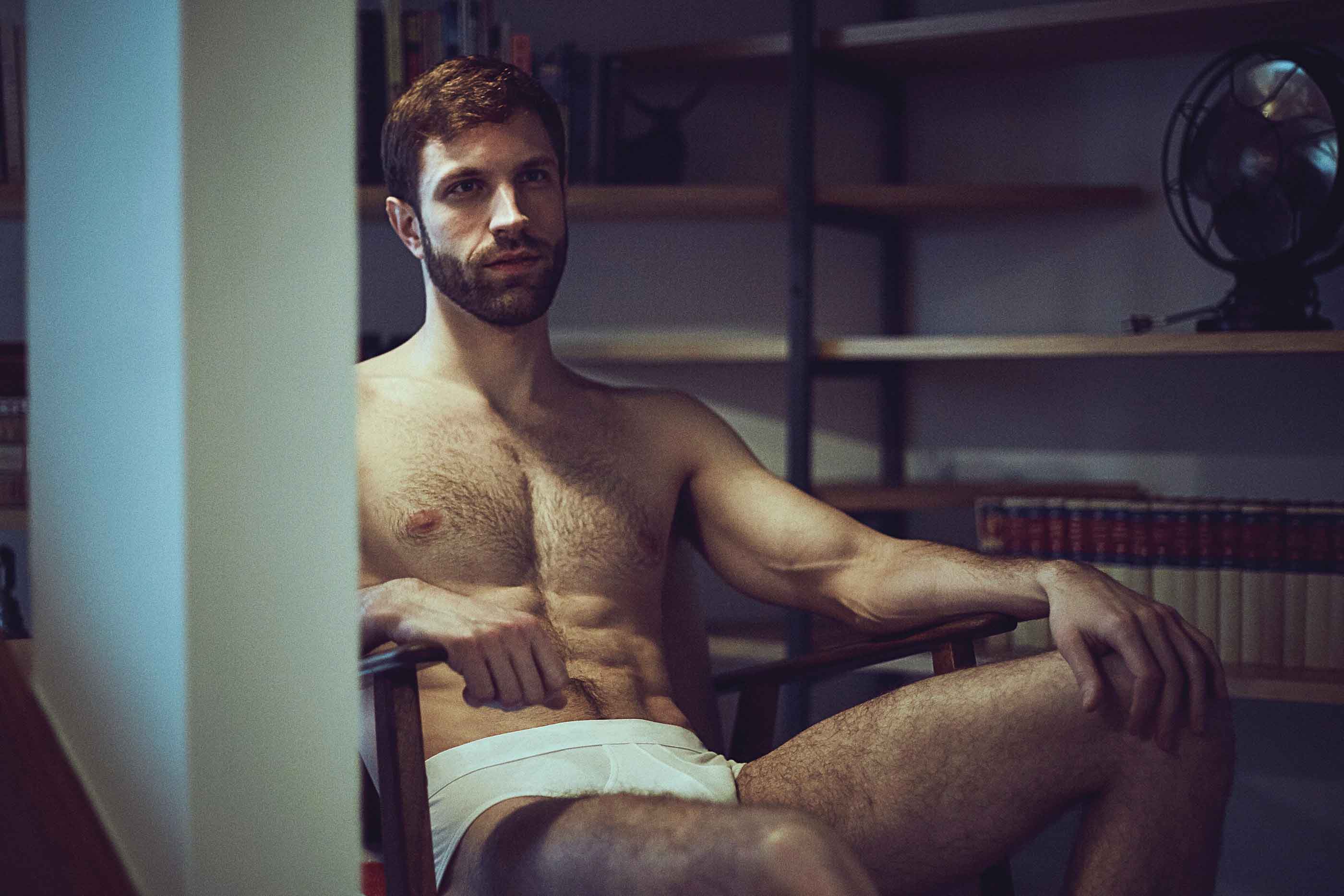 Man in white boxershorts sitting in a studio